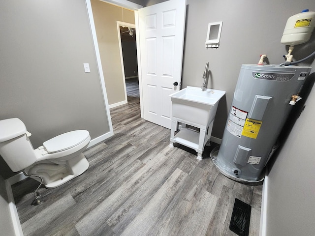 306 Johnson St, Lawrenceburg, TN 38464 - bathroom featuring water heater, wood finished floors, toilet, baseboards, and a sink