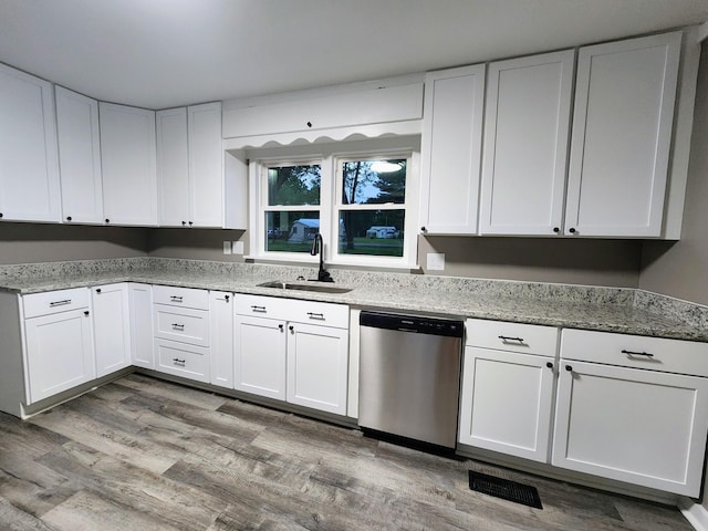 306 Johnson St, Lawrenceburg, TN 38464 - kitchen with stainless steel dishwasher, a sink, white cabinetry, light stone counters, and wood finished floors