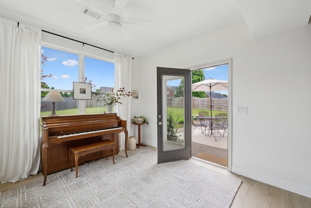 doorway featuring plenty of natural light, baseboards, ceiling fan, and light wood-style floors