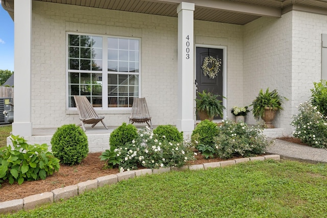 doorway to property with a porch and brick siding