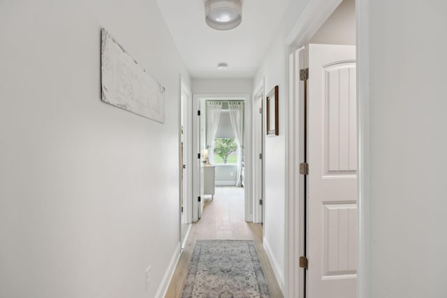 hall featuring light wood-style floors and baseboards