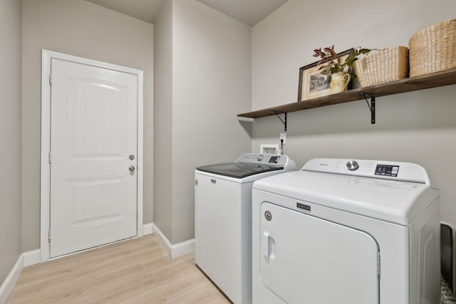 washroom featuring washing machine and clothes dryer, light wood-style flooring, and baseboards