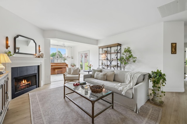 living room with light wood-style flooring, a tile fireplace, and baseboards