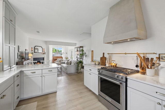 kitchen with high end stove, custom range hood, open floor plan, a peninsula, and light countertops