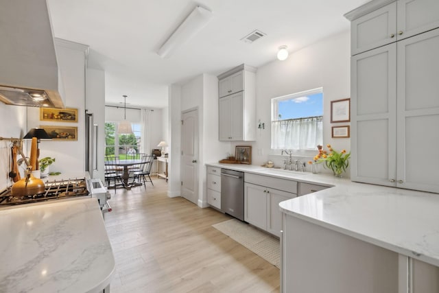 kitchen with a sink, dishwasher, wall chimney exhaust hood, light wood-style floors, and gray cabinets