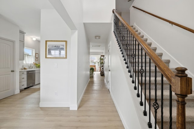 foyer featuring light wood finished floors, plenty of natural light, stairs, and baseboards