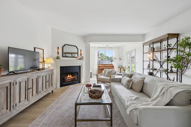 living area featuring light wood finished floors and a lit fireplace