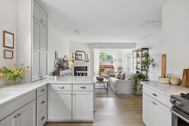 kitchen with a peninsula, open floor plan, stainless steel stove, and light countertops