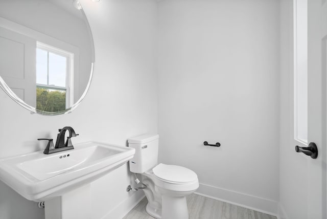 bathroom with baseboards, toilet, and a sink