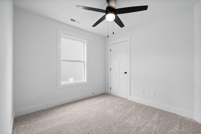 carpeted spare room with ceiling fan and baseboards