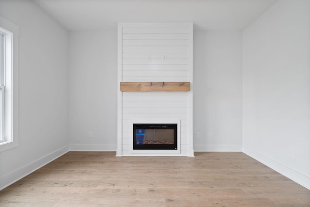 unfurnished living room featuring light wood-style floors, a fireplace, and baseboards