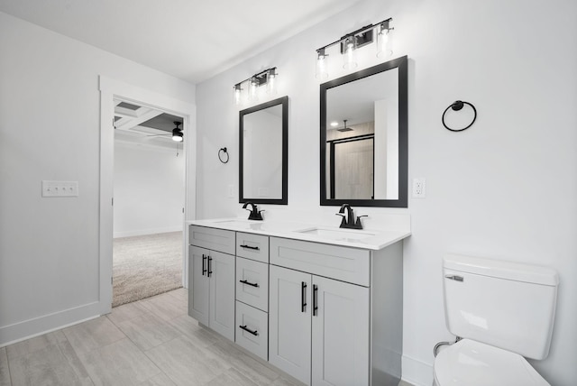 bathroom with ceiling fan, toilet, baseboards, and double vanity