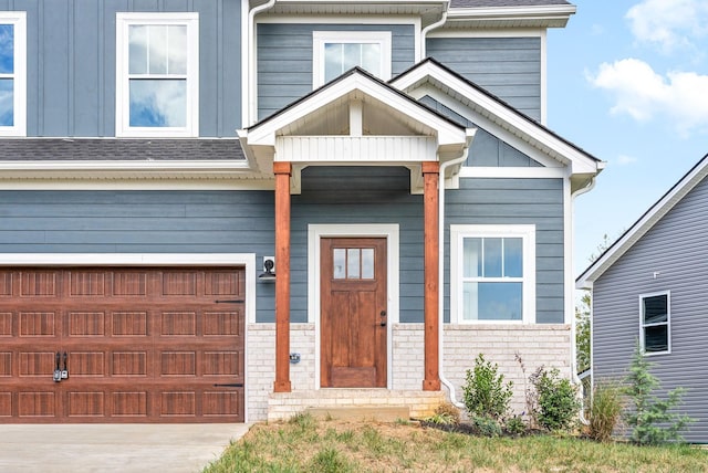 view of front of house with board and batten siding, an attached garage, brick siding, and driveway