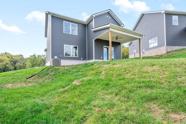 rear view of house with ceiling fan, a lawn, and cooling unit