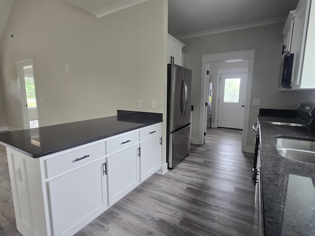 kitchen featuring freestanding refrigerator, a peninsula, light wood finished floors, ornamental molding, and white cabinetry