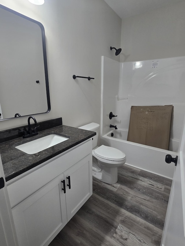 bathroom with vanity, wood finished floors, shower / bathtub combination, and toilet