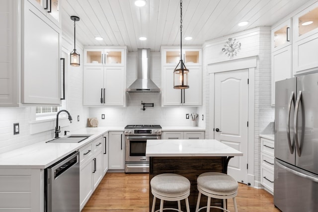 kitchen with appliances with stainless steel finishes, wall chimney range hood, a sink, backsplash, and recessed lighting