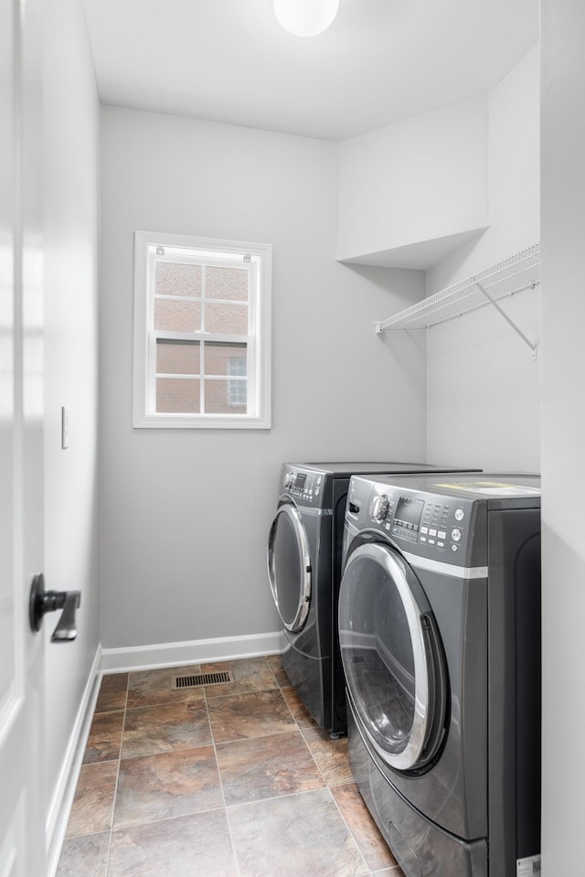 laundry room featuring washer and dryer, baseboards, and stone finish floors