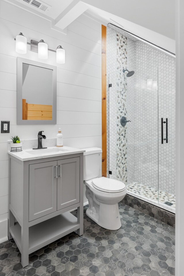 bathroom featuring a stall shower, toilet, wooden walls, and vanity