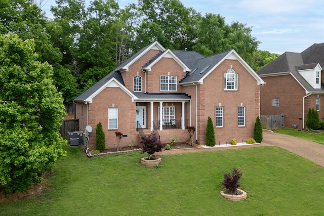 traditional home with brick siding, a porch, central AC, and driveway