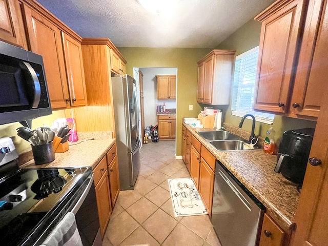 3517 Dobbins Pike, Portland, TN 37148 - kitchen featuring appliances with stainless steel finishes, a sink, light tile patterned flooring, and brown cabinets