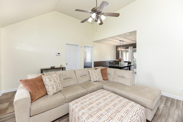 living area featuring ceiling fan, baseboards, wood finished floors, high vaulted ceiling, and a chandelier
