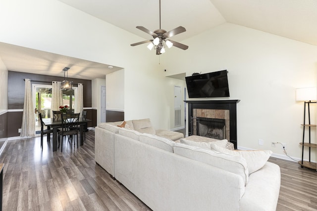 living room featuring wood finished floors, a tile fireplace, ceiling fan, baseboards, and high vaulted ceiling