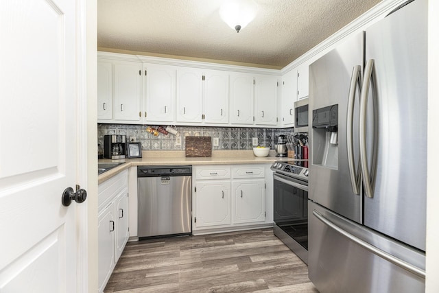 kitchen featuring appliances with stainless steel finishes, a textured ceiling, white cabinets, light wood-style flooring, and light countertops