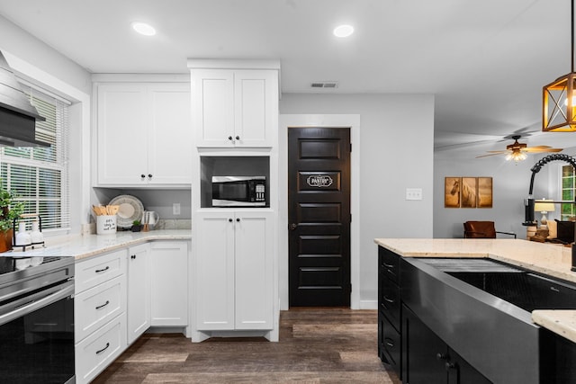 kitchen with appliances with stainless steel finishes, dark wood-style floors, a sink, light stone counters, and white cabinetry