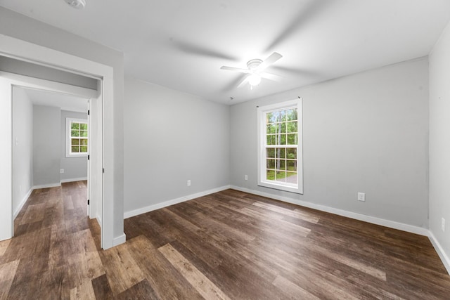 empty room with healthy amount of natural light, a ceiling fan, wood finished floors, and baseboards