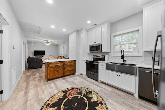 kitchen with stainless steel appliances, a sink, light wood-style flooring, white cabinetry, and recessed lighting