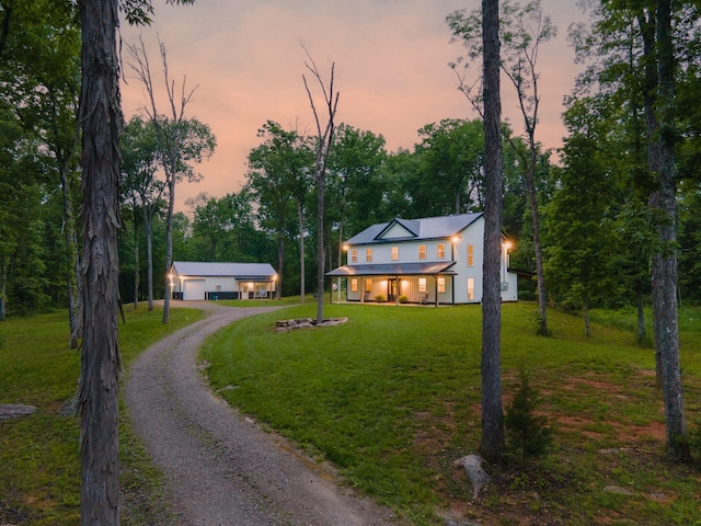 view of front facade with driveway, a porch, a detached garage, a yard, and stucco siding