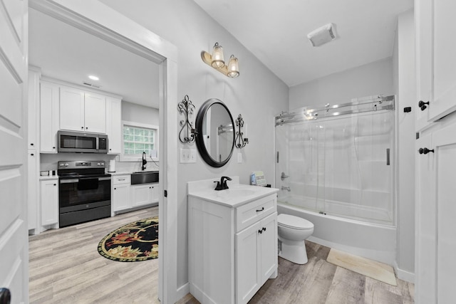 full bathroom featuring wood finished floors, vanity, toilet, and enclosed tub / shower combo