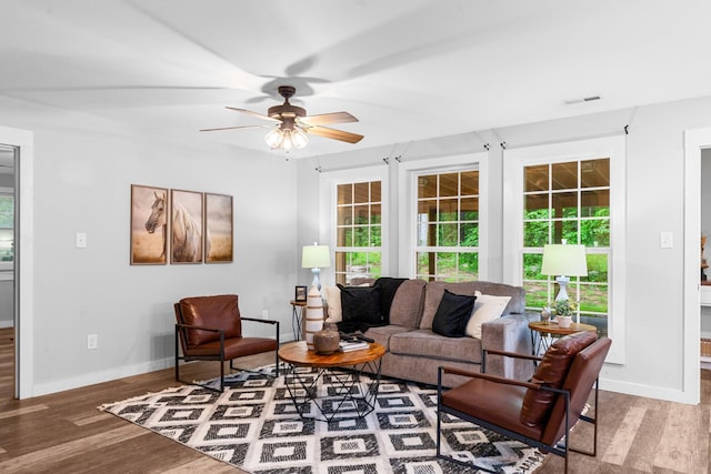 living area featuring wood finished floors, healthy amount of natural light, ceiling fan, and baseboards