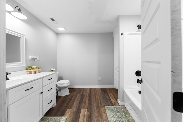 bathroom featuring wood finished floors, vanity, toilet, baseboards, and washtub / shower combination