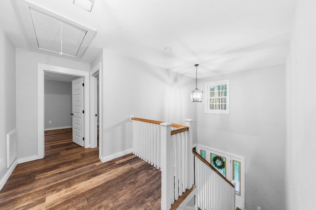 hall with an upstairs landing, attic access, wood finished floors, and baseboards