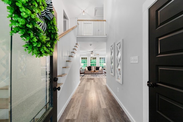 entryway featuring a ceiling fan, wood finished floors, stairway, and baseboards