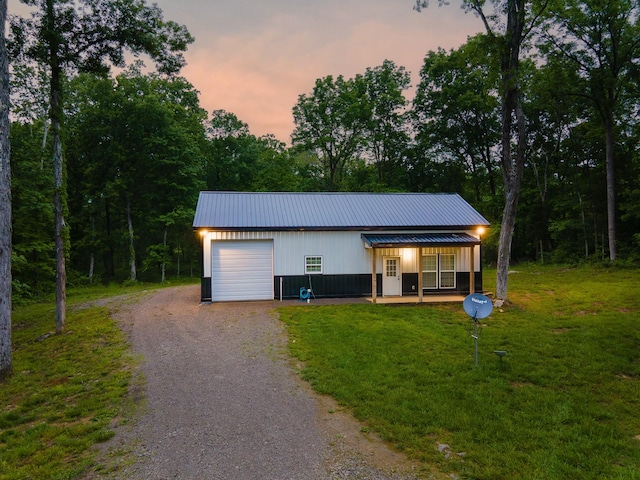view of front of property featuring metal roof, driveway, a lawn, and a garage