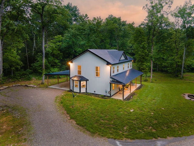 view of front of home with driveway, metal roof, a carport, a porch, and a front lawn