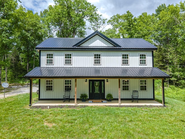 view of front of home with covered porch, a front yard, and metal roof