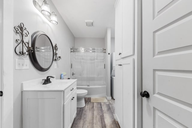 full bath featuring toilet, wood finished floors, vanity, and bath / shower combo with glass door