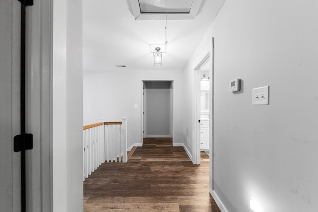 hall featuring attic access, wood finished floors, and baseboards