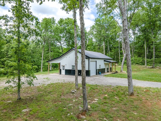 view of side of property with a garage, dirt driveway, and an outbuilding
