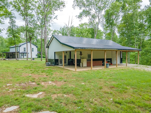 rear view of property featuring a yard, metal roof, central AC unit, a patio area, and french doors