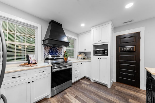 kitchen featuring stainless steel appliances, premium range hood, white cabinets, dark wood-type flooring, and light stone countertops