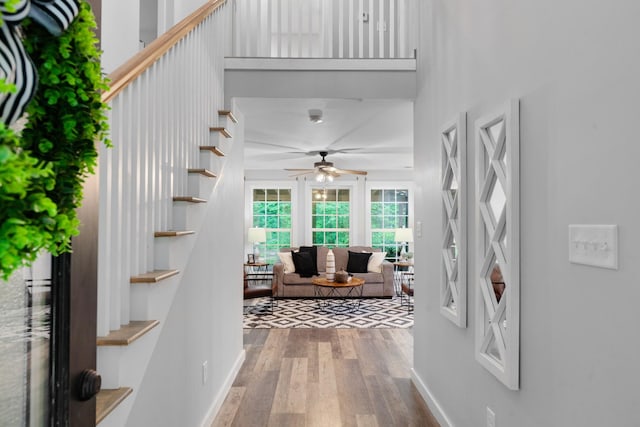entrance foyer featuring ceiling fan, wood finished floors, stairs, and baseboards