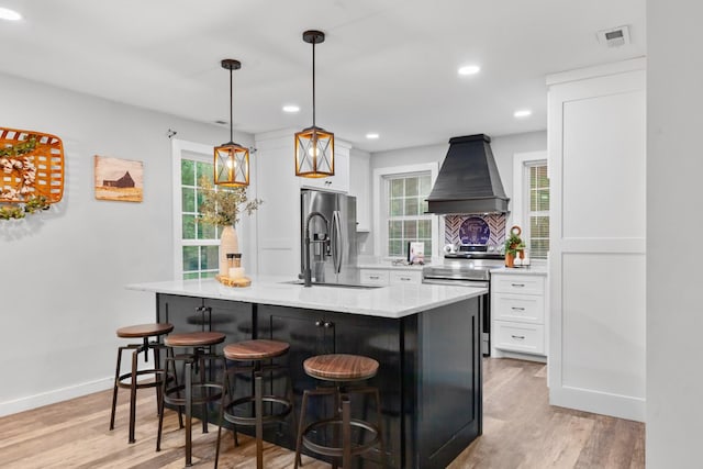 kitchen with appliances with stainless steel finishes, custom range hood, white cabinetry, light wood finished floors, and recessed lighting