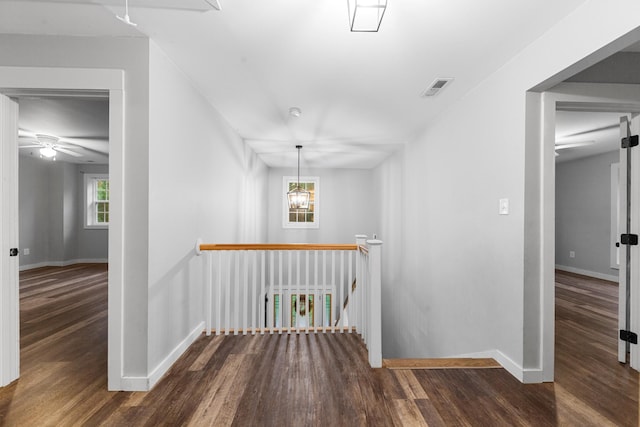 corridor with an upstairs landing, wood finished floors, and baseboards