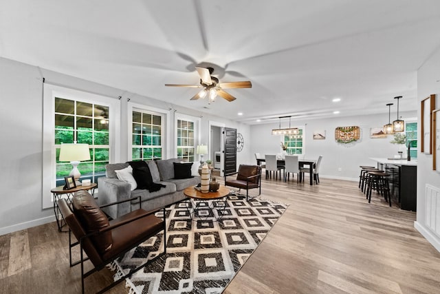 living room featuring light wood-type flooring, a ceiling fan, baseboards, and recessed lighting