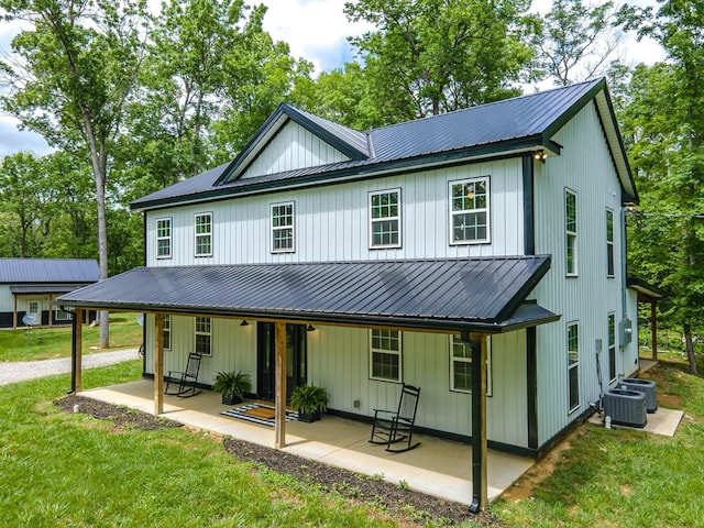 back of property featuring a lawn, metal roof, central AC unit, and a patio area